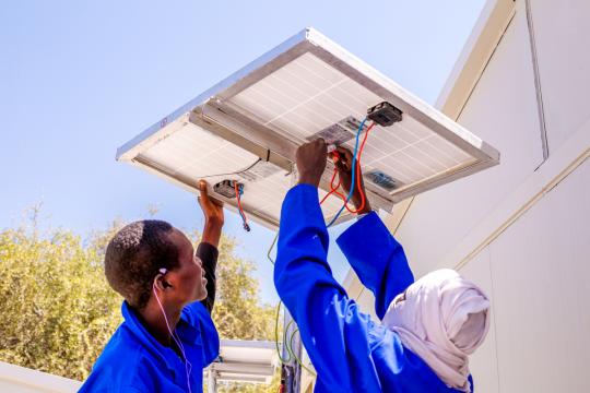 Deux hommes installent des panneaux solaires au Niger