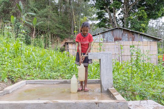 A girl collects clean water from a tap in rural Timor-Leste.