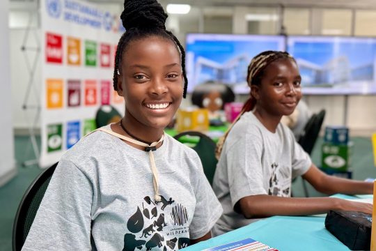 Two schoolgirls smiling at the camera while attending a climate youth event 