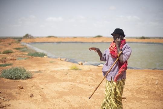 Camel herder, Mohamed Hirsi, beside the earth dam where his camels can now drink in the dry season. Photo: UNDP/Tobin Jones Man from Somalia next to water dam