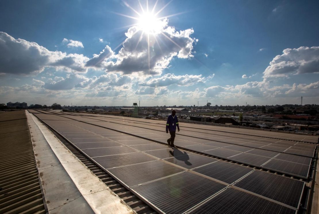 A technician services solar panels on the roof of a warehouse in Lusaka, Zambia.