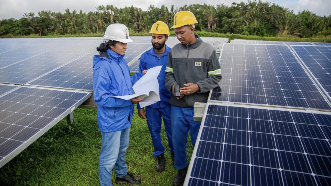 Femme ingénieur travaillant avec une équipe sur l'installation de panneaux solaires à l'île Maurice et aux Seychelles