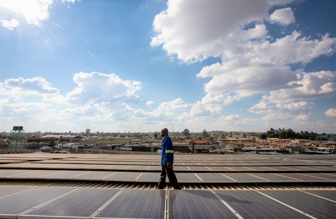 A technician walking on a roof installed with solar panels in Africa