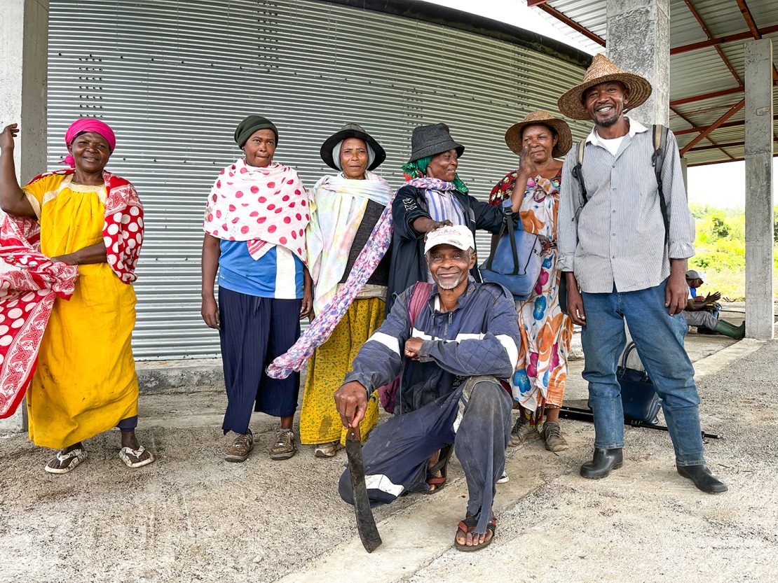 A group of smiling community members in Comoros stands in front of a water tank.
