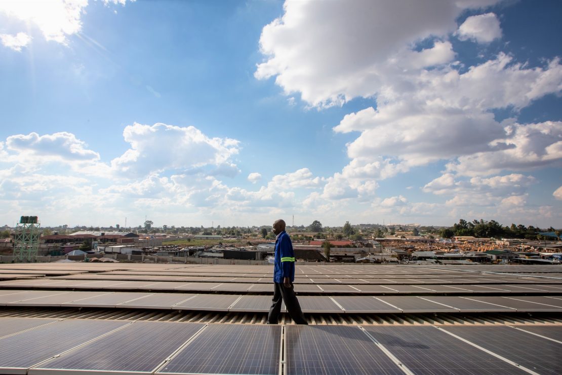 A technician walking on a roof installed with solar panels in Africa