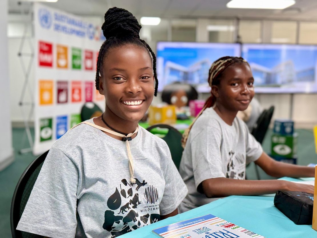 Two schoolgirls smiling at the camera while attending a climate youth event 
