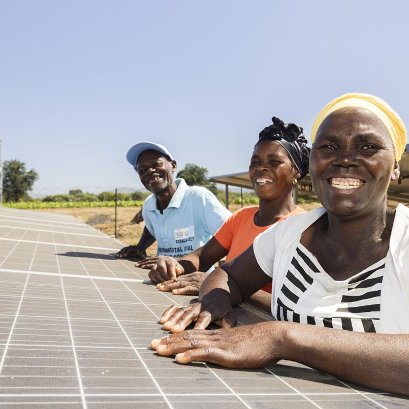 Three people standing by some solar panels