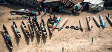 Fishermen and their families near their boats on a beach in Liberia