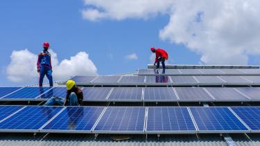 Des hommes installant des panneaux solaires sur un toit au Soudan du Sud