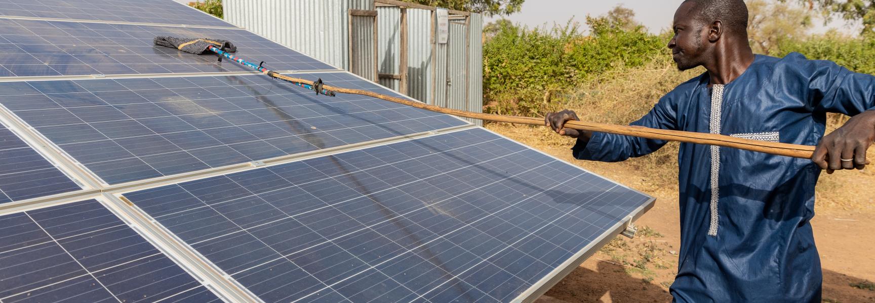 Hombre limpiando un panel solar en Mali