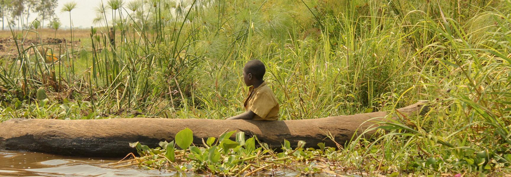A child in a small boat by the river in Rwanda